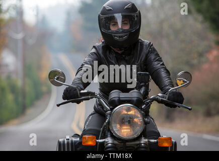 1900 femelle portant un casque moto en roulant sur route Banque D'Images