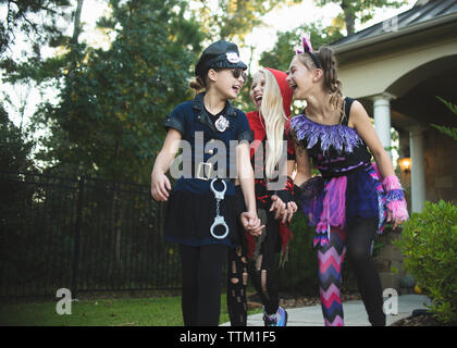 Happy friends dans Halloween costumes tenant la main tout en marchant à la cour Banque D'Images