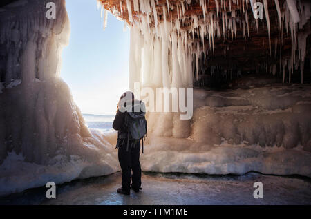 Vue arrière de la femme debout dans la caverne de glace Banque D'Images