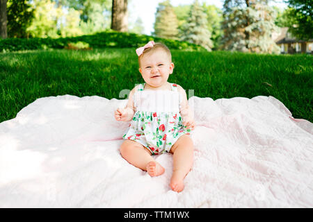 Un bébé rit alors qu'il était assis sur une couverture à l'extérieur Banque D'Images