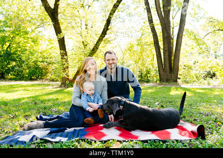 Une famille est assis sur une couverture à l'extérieur avec leur chien braque de Banque D'Images