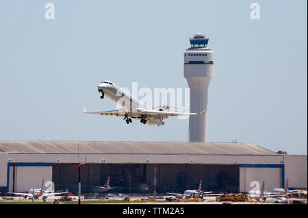 Un avion de passagers d'American Eagle décolle de l'aéroport international Charlotte-Douglas avec un service support et tour de contrôle à l'arrière-plan. Banque D'Images