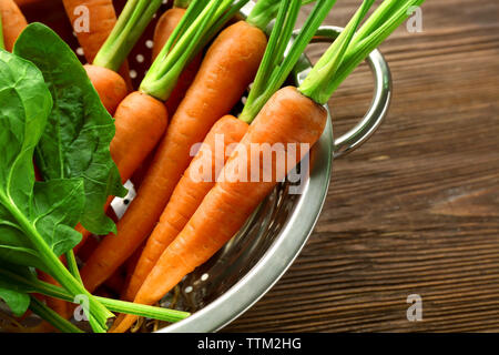 Les carottes à l'oseille dans une passoire sur table en bois Banque D'Images