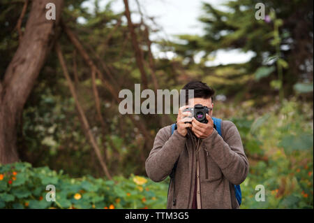 Male hiker photographing in forest Banque D'Images