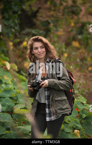 Female hiker holding camera in forest Banque D'Images