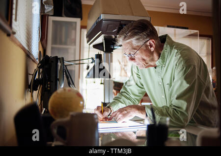 L'homme principal travaillant sur tablette graphique à la maison Banque D'Images