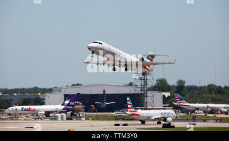 Un jet commercial American Eagle s'exécute à partir d'un occupé l'aéroport international Charlotte-Douglas dans un ciel sans nuages, ciel bleu. Banque D'Images