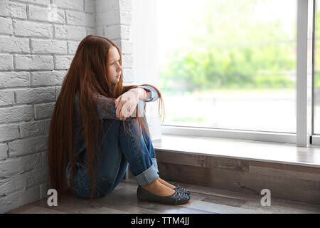 Triste fille assise près de window Banque D'Images