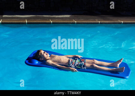 Portrait of boy détente sur radeau dans la piscine Banque D'Images