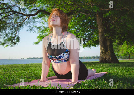 Low angle view of woman on exercise mat pose cobra at park Banque D'Images
