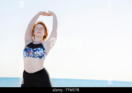 Woman stretching tout en exerçant à la clear sky Banque D'Images