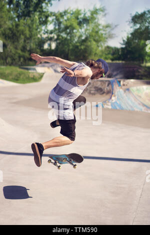 Jeune homme faisant du skateboard trick sur la rampe Banque D'Images