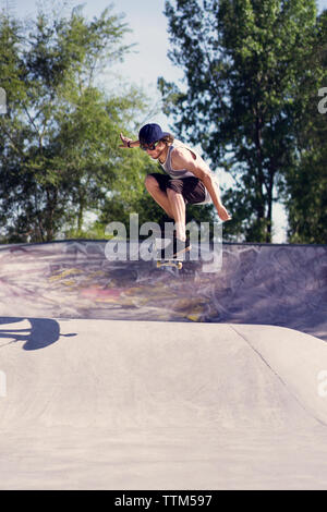 Jeune homme faisant du skateboard trick sur la rampe Banque D'Images