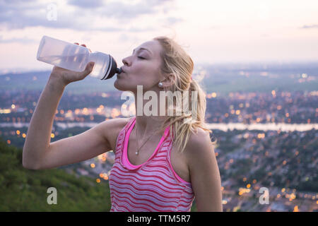 Female hiker l'eau potable de la bouteille réutilisable en haut de montagne lors d'une randonnée en soirée dans l'Est du Canada Banque D'Images