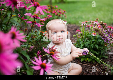 High angle portrait of cute baby girl sitting in jardin des plantes au milieu Banque D'Images