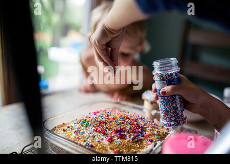 Girl decorating cake fraîchement préparés avec beaucoup d'arrose Banque D'Images