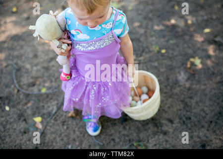 Girl carrying basket marche d'oeufs frais et baby doll Banque D'Images