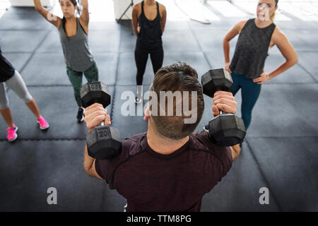 Les athlètes de l'instructeur pour soulever les haltères expliquant en gym crossfit Banque D'Images