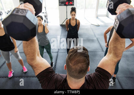 Haltères de levage de l'instructeur au moment d'expliquer à des athlètes de sport crossfit Banque D'Images