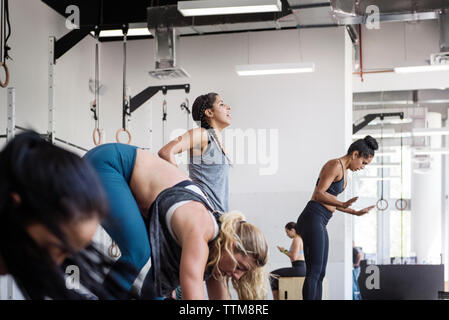 Les femmes faisant de l'exercice dans la salle de sport crossfit burpee Banque D'Images