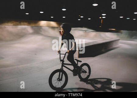 Boy riding bicycle au parc de planche à roulettes Banque D'Images