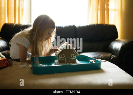 Girl decorating toy house tandis que le canapé à la maison Banque D'Images