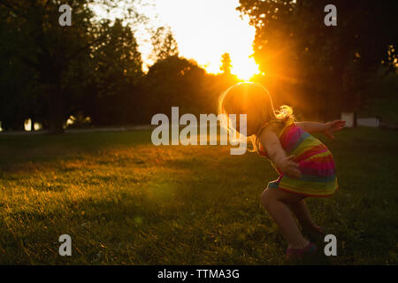 Happy Girl Dancing on grassy field pendant le coucher du soleil Banque D'Images