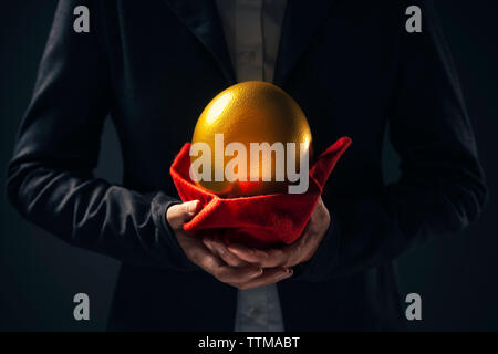 Gros oeuf d'or dans les mains de businesswoman agissant en tant qu'actionnaire ou investisseur dans l'investissement des entreprises Banque D'Images