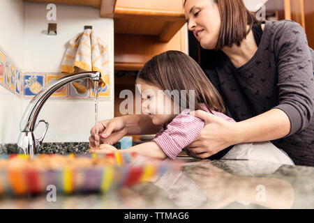 Mère lave-girl's hands in kitchen Banque D'Images