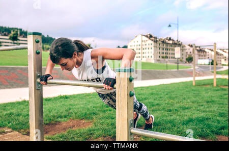 Woman doing push-ups sur la gymnastique bar du Park Banque D'Images