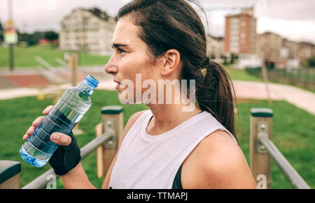 Woman tout en tenant la bouteille d'eau au parc Banque D'Images