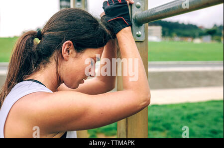 Tired woman leaning against gymnastics bar du Park Banque D'Images