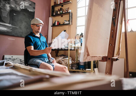 L'homme travaillant comme peintre à la recherche à l'image de référence pour la nouvelle peinture Banque D'Images