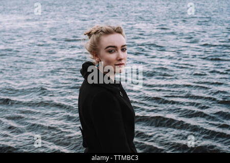 Vue de côté portrait of young woman standing by river in city Banque D'Images