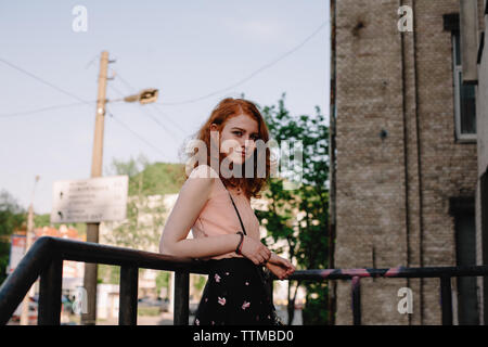 Portrait of young redhead woman by railing in city Banque D'Images