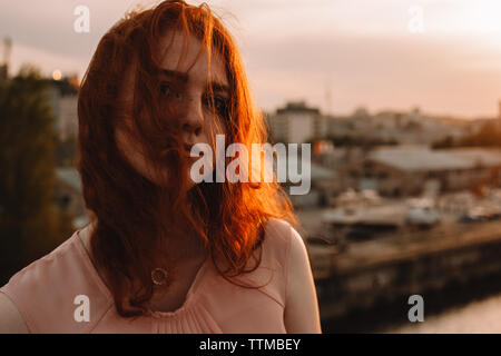 Portrait de jeune femme avec cheveux tête rouge sur la face au coucher du soleil