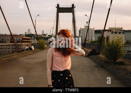 Portrait of smiling redhead woman standing on bridge en ville Banque D'Images