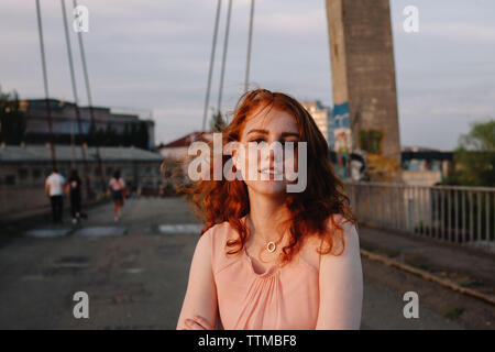 Portrait of teenage girl with red hair debout sur bridge en ville Banque D'Images