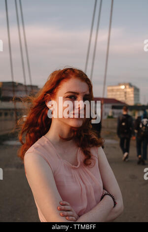 Portrait of young woman with arms crossed standing sur bridge en ville Banque D'Images