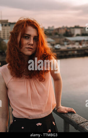 Portrait de jeune femme aux cheveux rouges l'article by railing on bridge Banque D'Images