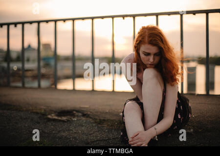 Portrait of teenage girl sitting on bridge au coucher du soleil Banque D'Images