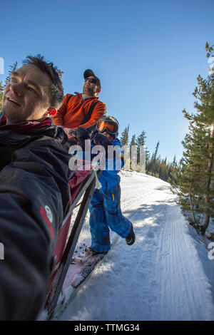 USA (Oregon, Bend, un jeune garçon se tient avec le musher sur les marchepieds, tout en étant tiré autour de Mt. Les chiens de traîneau par Baccalauréat Banque D'Images