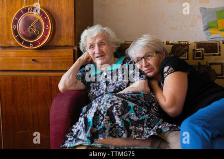 Femme Russe avec sa fille adulte assis ensemble à la maison à regarder à la télévision le discours de Poutine. Banque D'Images