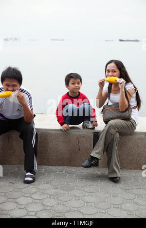 PHILIPPINES, Manille, famille bénéficie de certains maïs à la Baie à pied Rojas Blvd Banque D'Images