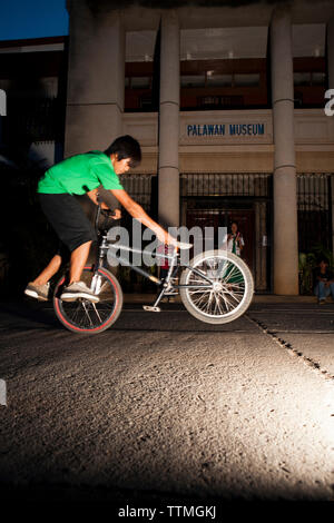 PHILIPPINES, Palawan, Puerto Princesa, garçon ne astuces sur son vélo dans le centre de Puerto Princessa près de l'Amphithéâtre Mitra Banque D'Images