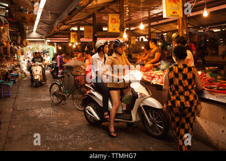 VIETNAM, Hanoi, les jeunes femmes à cesser leur cyclomoteur à acheter de la viande chez le boucher au marché Chau Long Banque D'Images