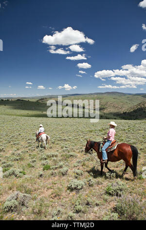 USA, Wyoming, du cantonnement, un cowboy et cowgirl ride à travers un paysage sans fin, Abara Ranch Banque D'Images