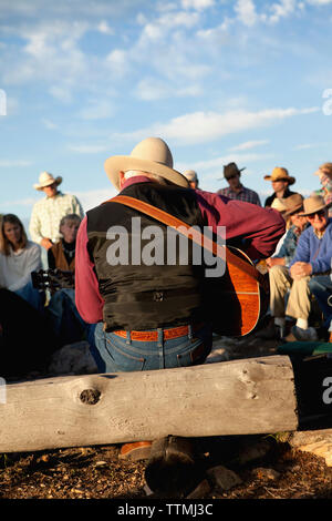 USA, Wyoming, du cantonnement, réduite à un ranch s'asseoir autour d'un feu de camp et d'écouter un homme jouer de la guitare et chanter des chansons country western, Abara Ranch Banque D'Images