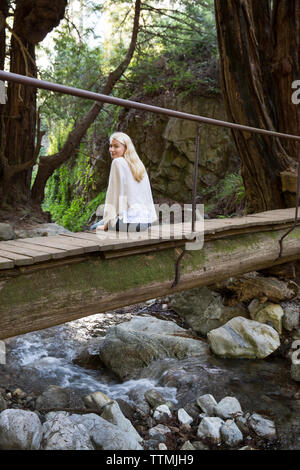 États-unis, Californie, Big Sur, Esalen, une femme assise sur un petit pont sur Hot Springs Creek à l'Institut Esalen Banque D'Images