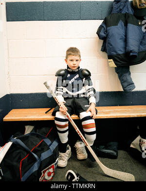 CANADA, BC Rockies, garçon de vestiaire holding ice hockey stick, portrait, Fernie Banque D'Images